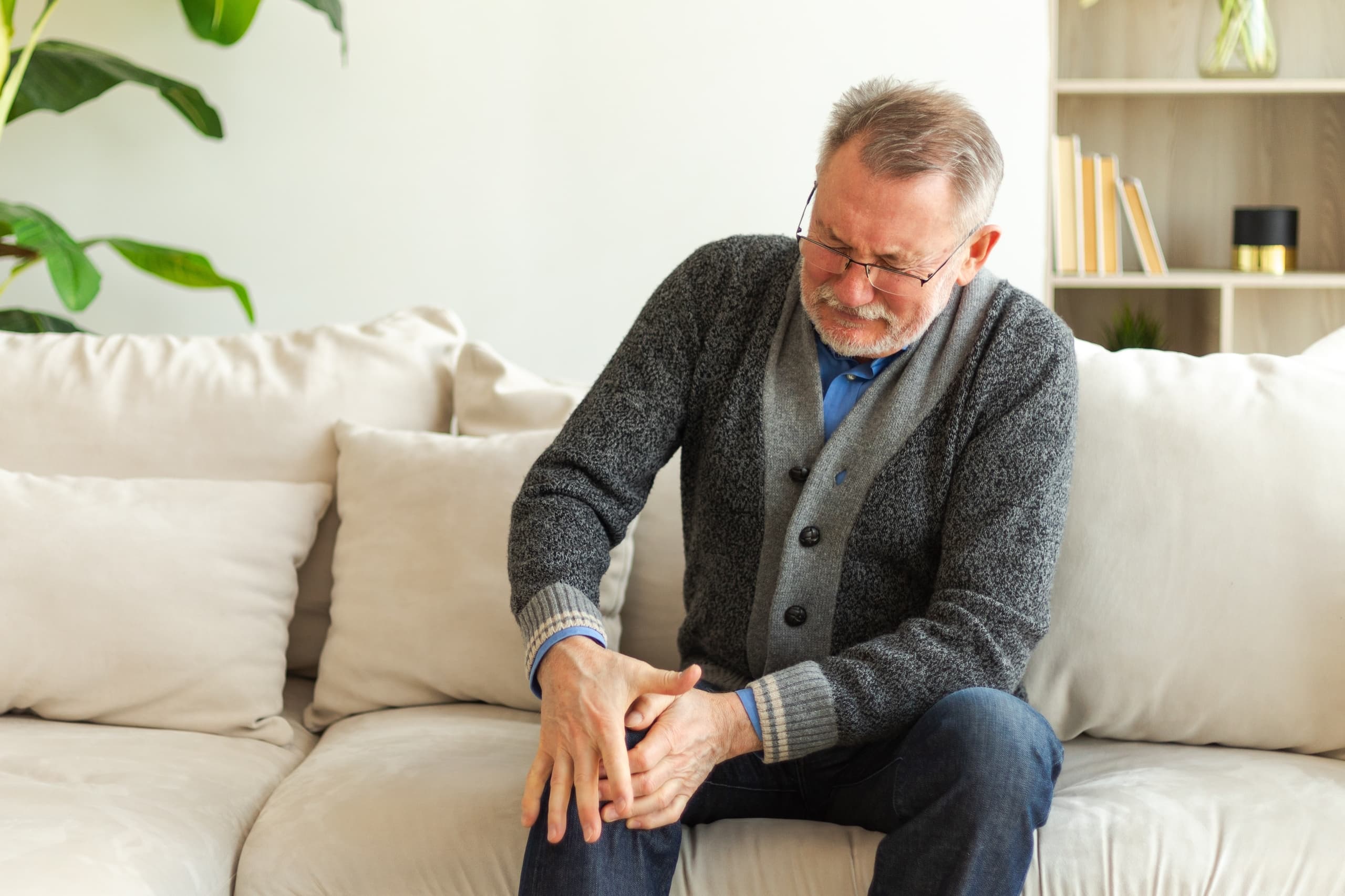 A man winces as he grasps his knee