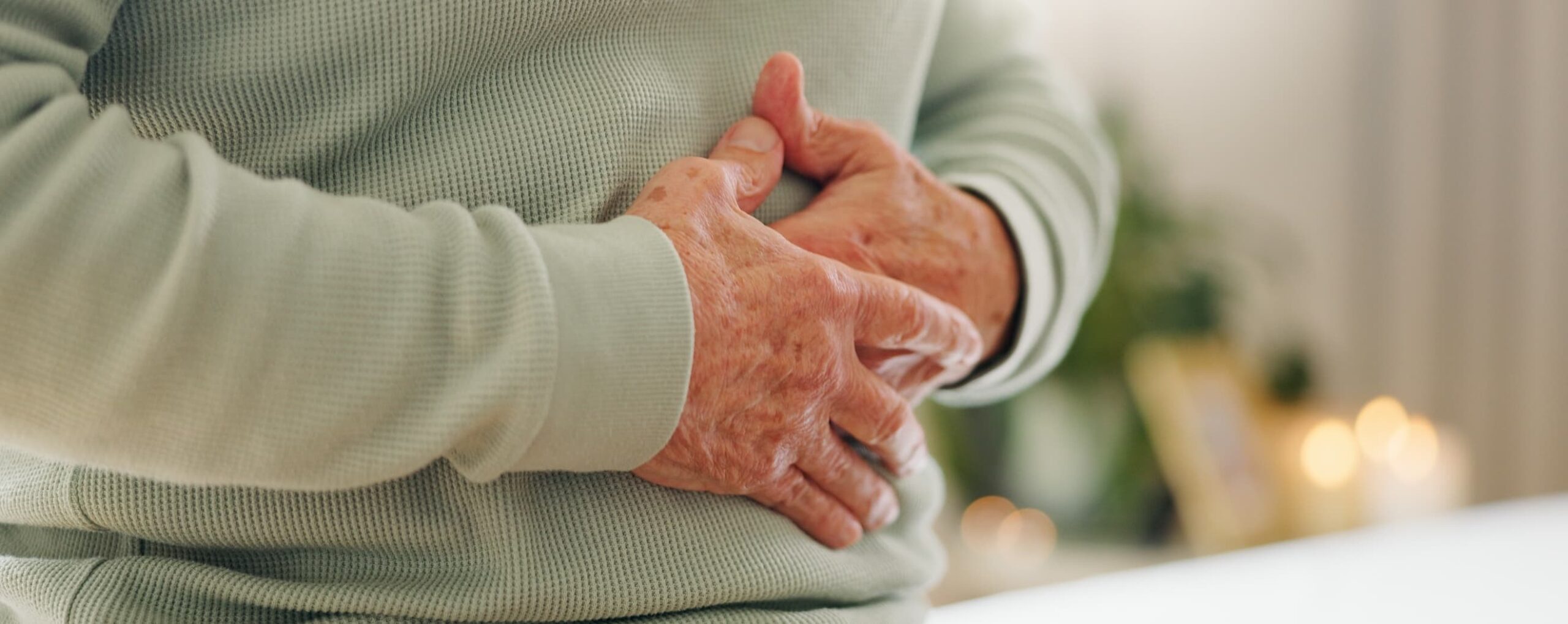 An older person holds their belly with both hands