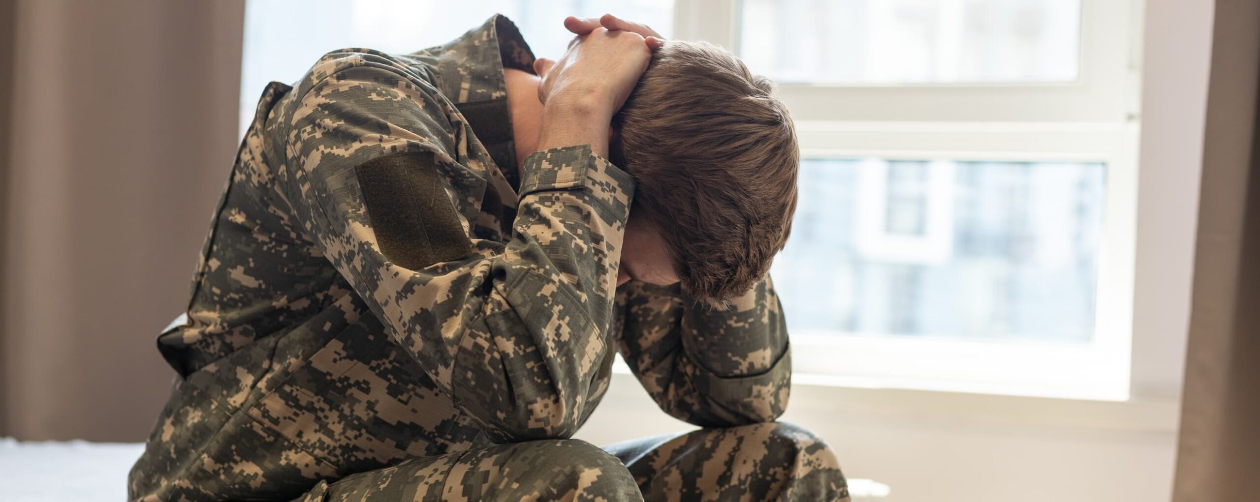 A military man holds his head in it hands bending over